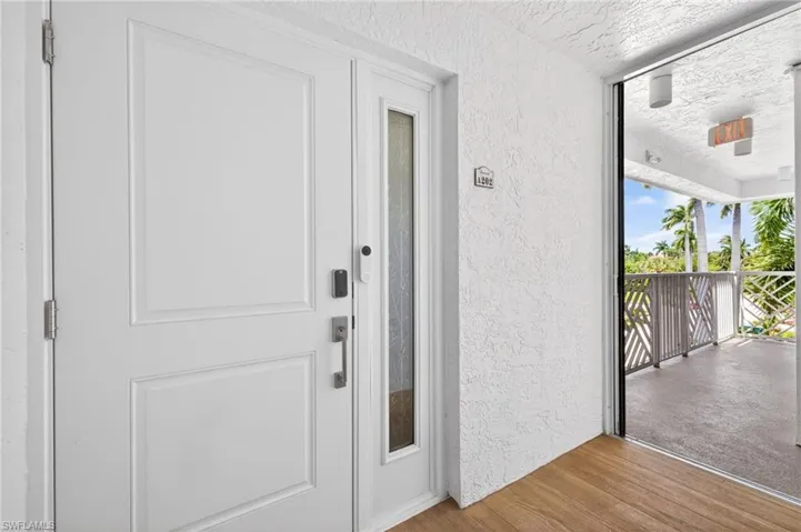 Entryway featuring a white paneled door with an adjacent frosted glass sidelight and a door number plaque