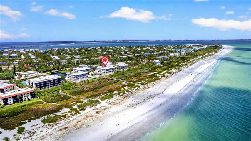 Aerial view of the property located on a coastline with a sandy beach and turquoise water