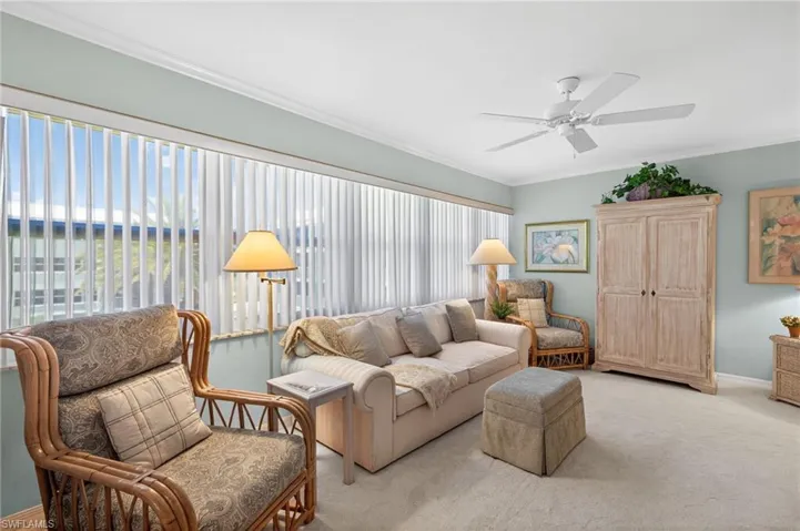 Den featuring a ceiling fan, crown molding, and large windows with vertical blinds