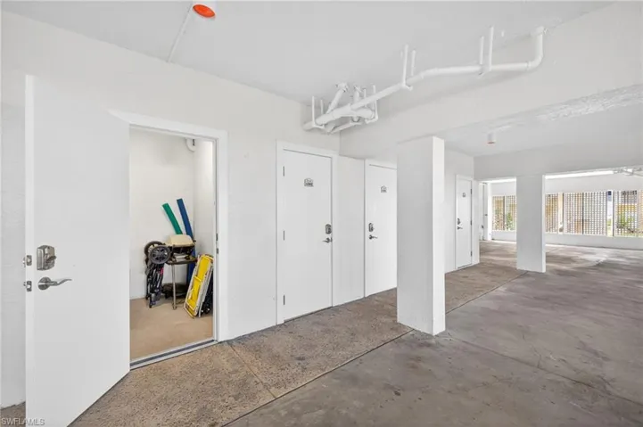 Storage area featuring white walls, concrete flooring, and multiple white doors