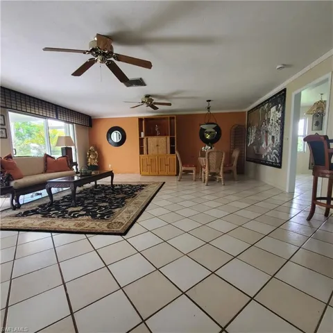 Living area with crown molding, light tile patterned floors, and ceiling fan
