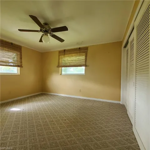 Unfurnished bedroom with a closet, ornamental molding, carpet flooring, and a ceiling fan
