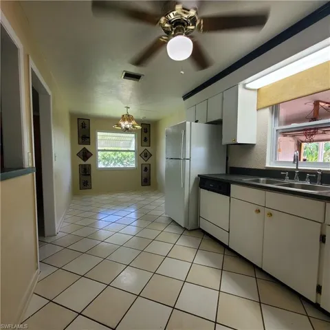 Kitchen with white appliances, white cabinets, healthy amount of natural light, and dark countertops