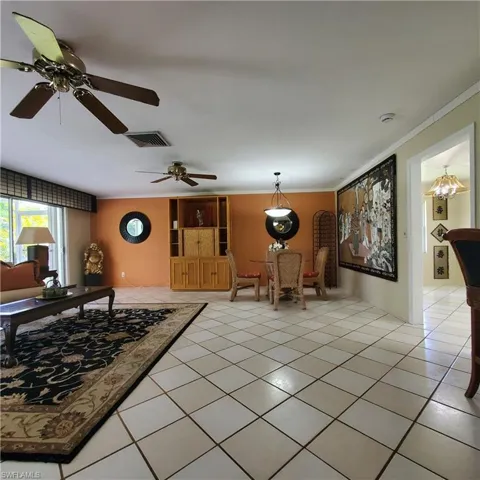 Living room with crown molding, light tile patterned flooring, and ceiling fan