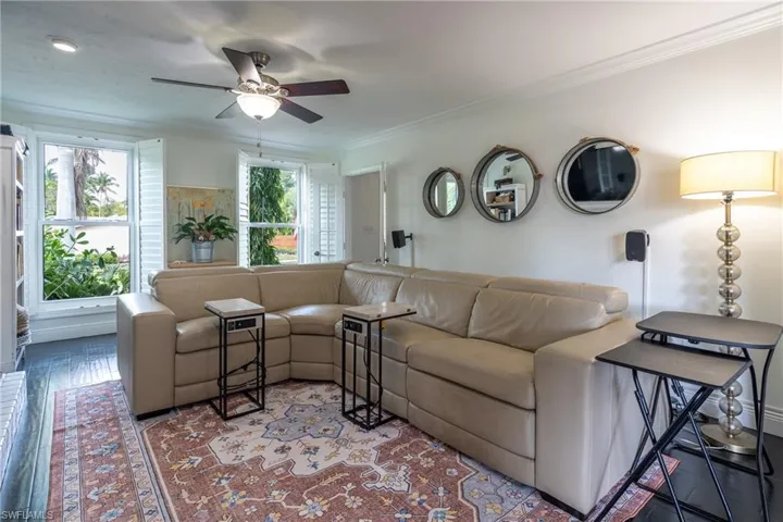 Living area with ceiling fan, wood-type flooring, and ornamental molding