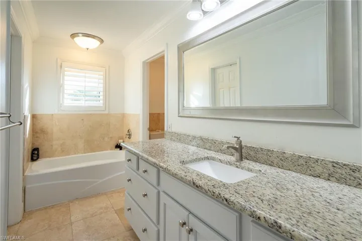 Full bathroom featuring vanity, crown molding, a garden tub, and tile patterned floors