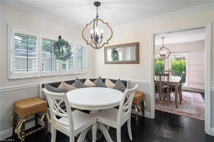 Dining room featuring dark wood finished floors, ornamental molding, baseboards, and a chandelier