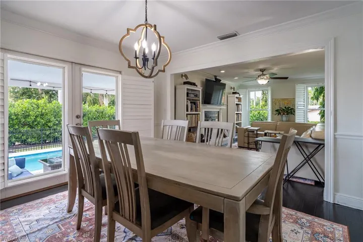 Dining room with visible vents, ornamental molding, ceiling fan with notable chandelier, dark wood finished floors, and a fireplace