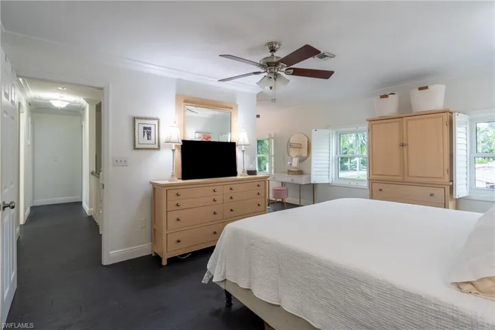 Bedroom featuring multiple windows, crown molding, and dark wood-type flooring