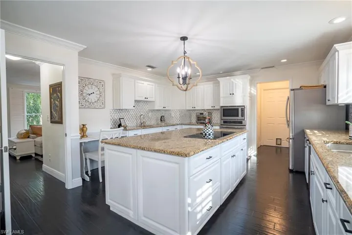 Kitchen featuring ornamental molding, a sink, white cabinets, appliances with stainless steel finishes, and a center island