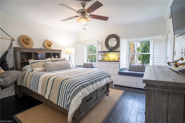 Bedroom with a ceiling fan, dark wood-style flooring, and ornamental molding