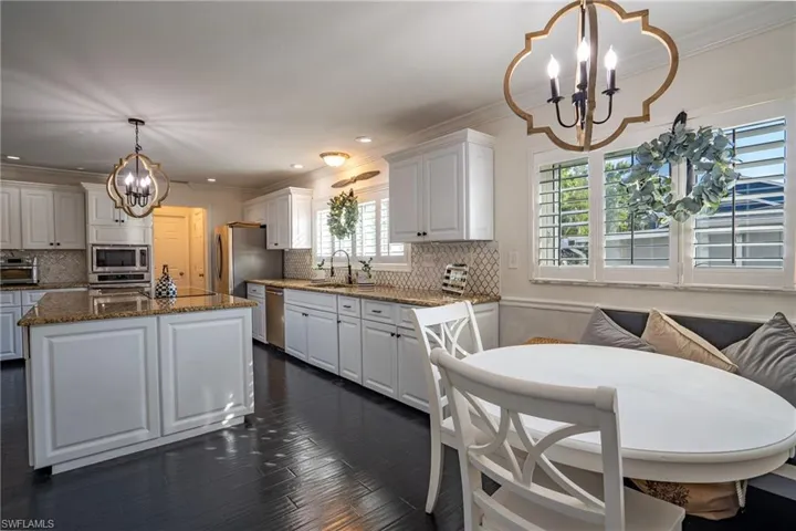 Kitchen featuring a notable chandelier, appliances with stainless steel finishes, crown molding, and white cabinetry