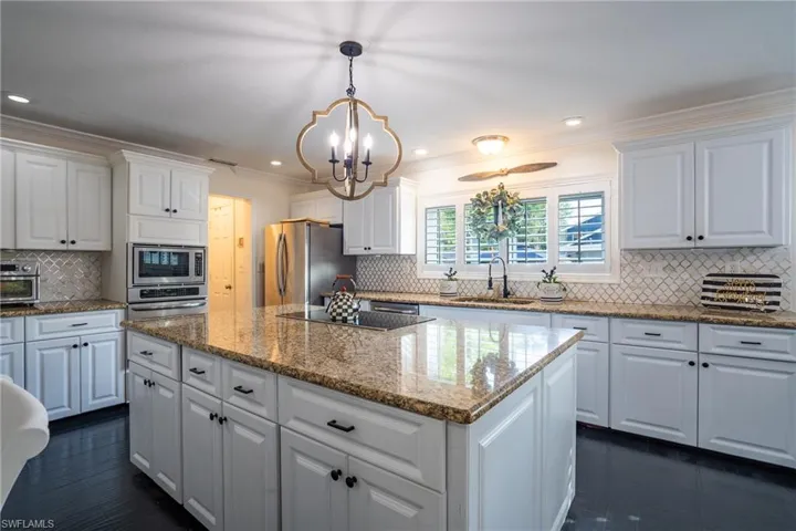 Kitchen with a center island, crown molding, appliances with stainless steel finishes, a notable chandelier, and a sink