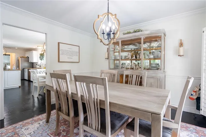 Dining room featuring dark wood finished floors, a notable chandelier, and ornamental molding