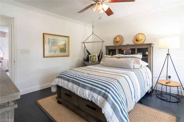 Bedroom featuring dark wood-style flooring, baseboards, and ornamental molding