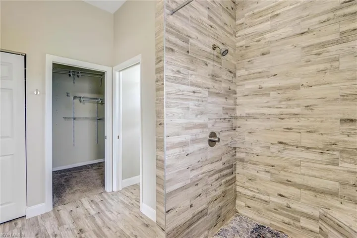 Walk-in shower featuring wood-look tile surround and mosaic tile flooring