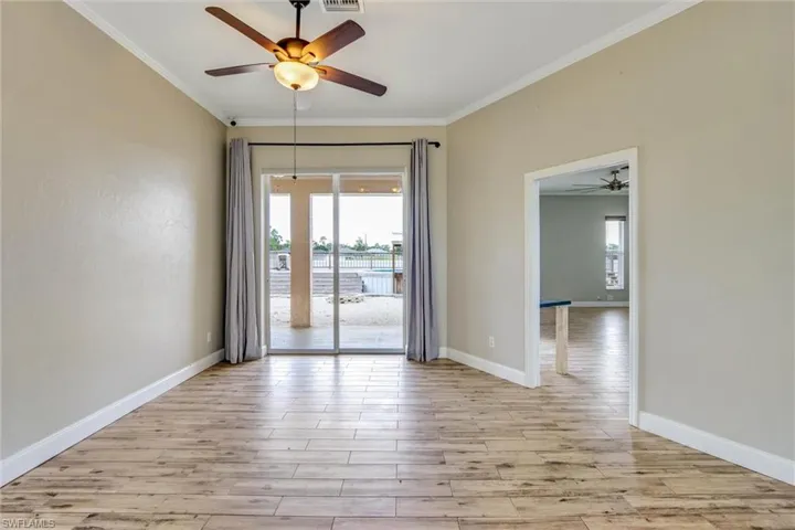 Interior room featuring wood-finish flooring, light neutral-toned walls, and white crown molding