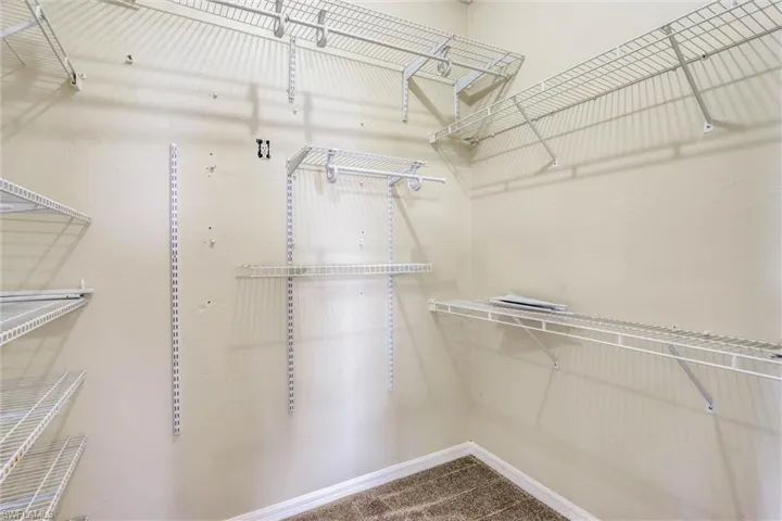 Walk-in closet featuring wire shelving, multiple hanging rods, and neutral wall paint