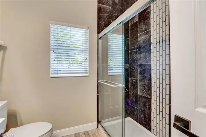 Shower enclosure featuring dark marbled tile, a vertical accent of white subway tile, and a sliding glass door