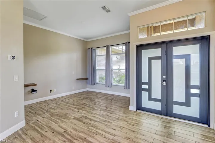 Entryway featuring modern double doors with frosted glass panels and a decorative transom window above
