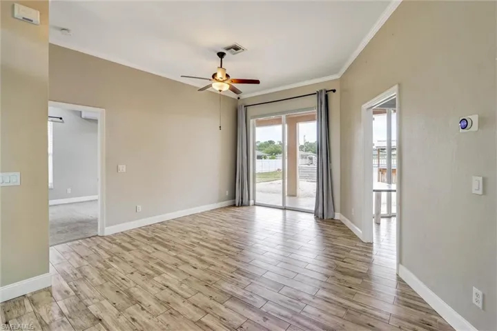 Spacious interior featuring wood-finish flooring, crown molding, and a ceiling fan