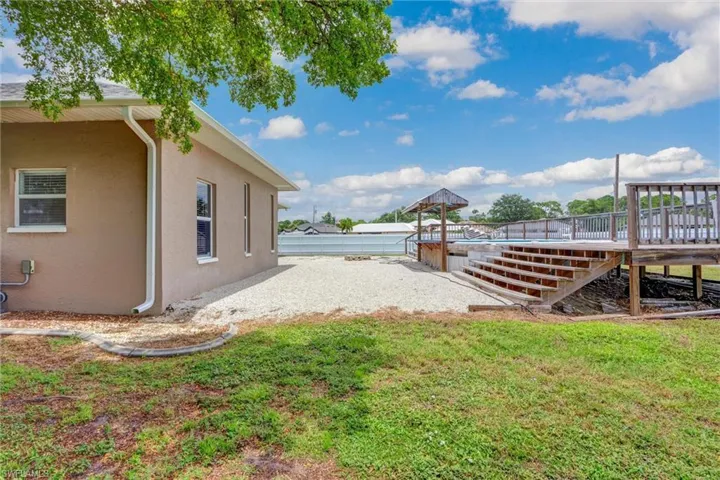 Expansive exterior featuring a wood deck with railings, a built-in gazebo, and a gravel patio area