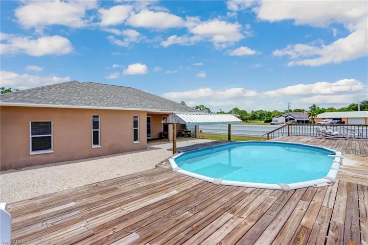 Expansive wood-finish deck surrounds an above-ground swimming pool