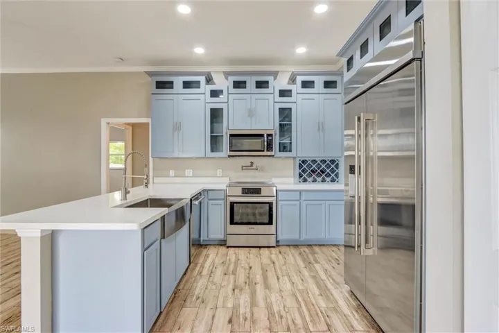 Gourmet kitchen with light blue cabinetry, stainless steel appliances, and a farmhouse sink
