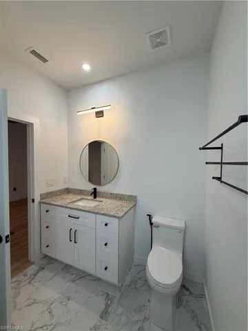 Half bathroom featuring vanity, light marble finish flooring, and recessed lighting