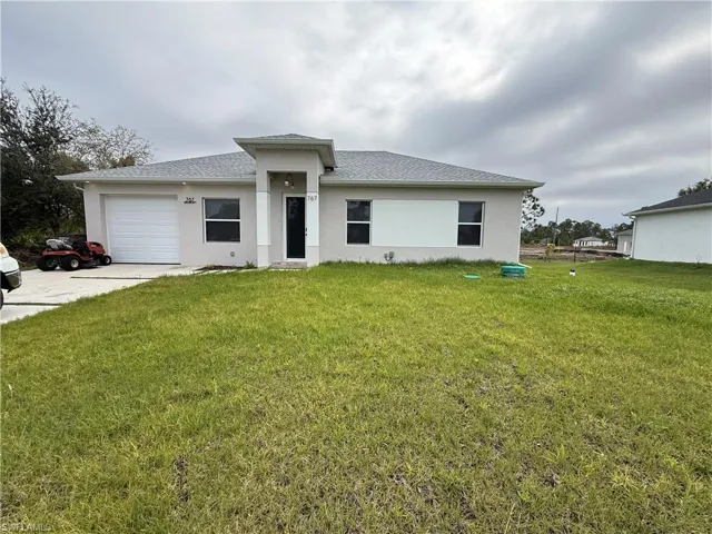 Prairie-style house with an attached garage, stucco siding, a front yard, and driveway