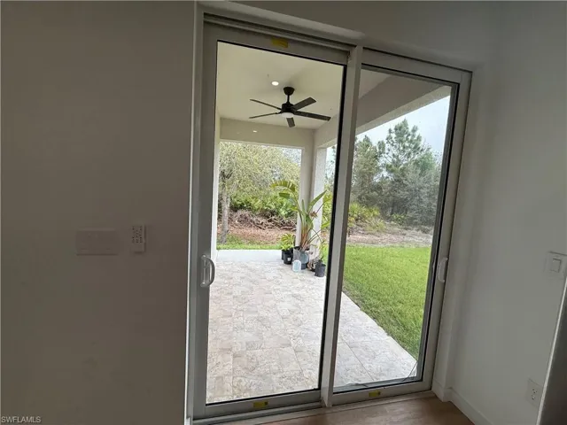 Doorway to outside with ceiling fan and baseboards