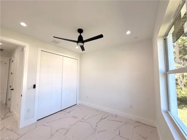 Unfurnished bedroom featuring light marble finish flooring, a ceiling fan, a closet, and recessed lighting