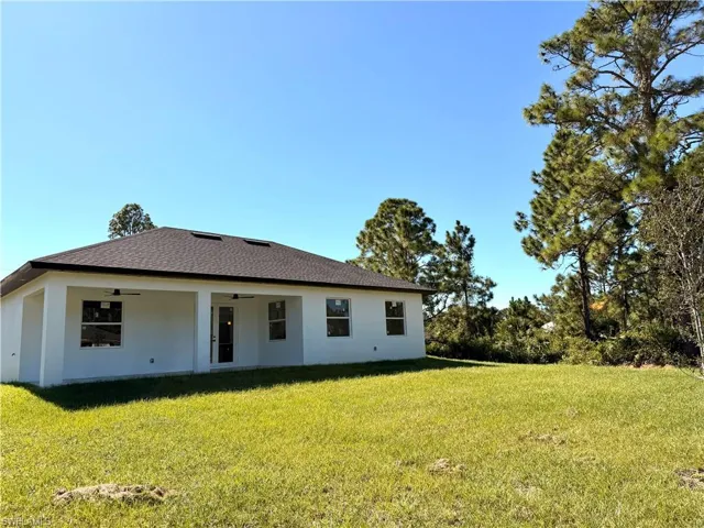 View of front facade with a front yard, stucco siding, a patio, and a ceiling fan