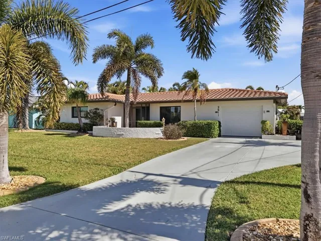 View of front of property with an attached garage, driveway, stucco siding, a front yard, and a tiled roof