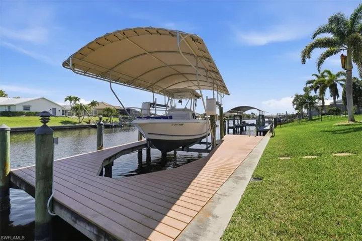 Dock with a lawn, boat lift, and a water view