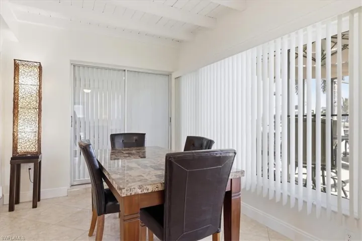 Dining space featuring light tile patterned floors and a wooden ceiling with exposed beams