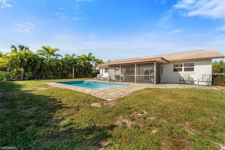 Back of property with a sunroom, an outdoor pool, a lawn, and a patio area