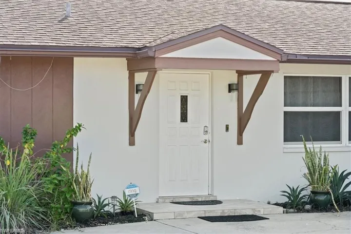 Entrance to property featuring a shingled roof and stucco siding