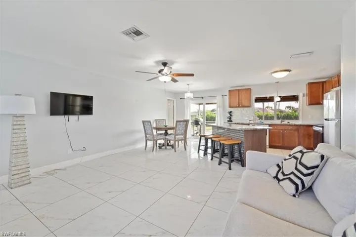 Living room with light marble finish floors, a ceiling fan, and baseboards
