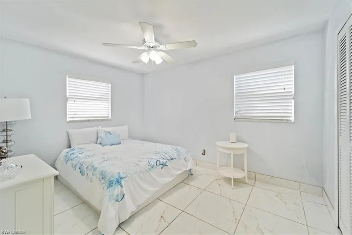 Bedroom featuring marble look tile flooring, ceiling fan, and a closet