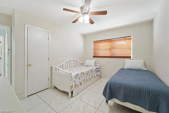 Bedroom with a ceiling fan and marble look tile flooring