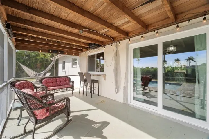 Sunroom featuring beamed ceiling and an outdoor living space