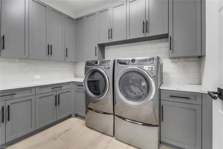 Washroom featuring independent washer and dryer, light hardwood / wood-style floors, and cabinets