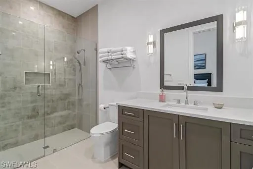 Bathroom featuring vanity, toilet, walk in shower, and tile patterned flooring