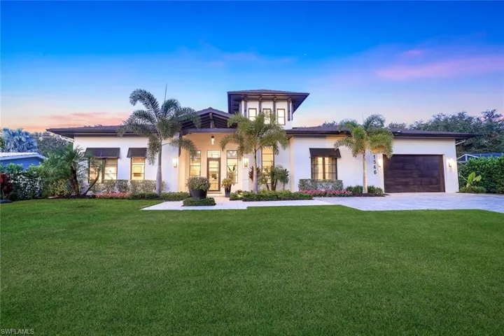 View of front of property featuring an attached garage, decorative driveway, stucco siding, and a yard