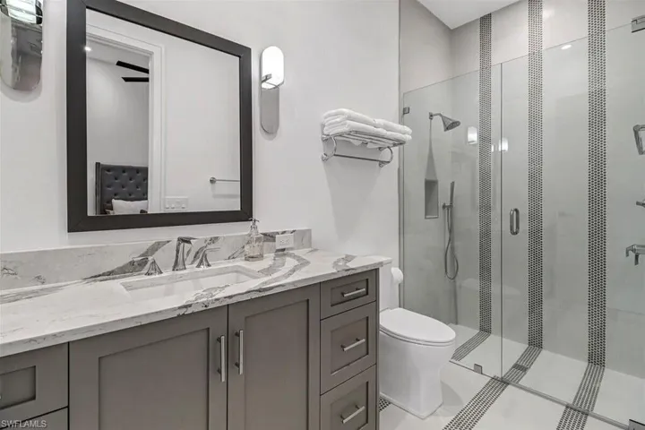 Bathroom with vanity, an enclosed shower, and toilet
