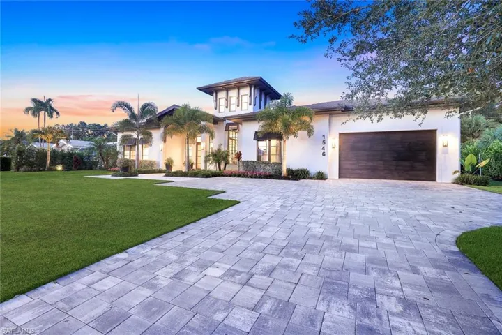 Contemporary house with decorative driveway, a garage, stucco siding, and a lawn