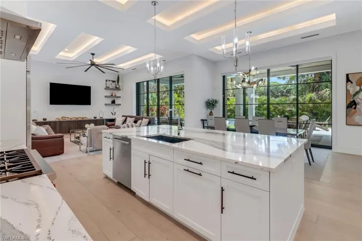 Kitchen featuring a healthy amount of sunlight, light stone counters, sink, and pendant lighting