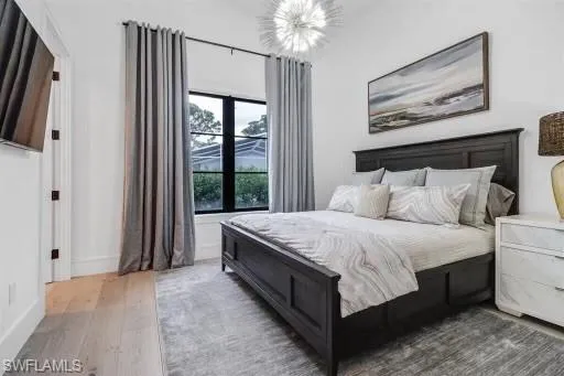 Bedroom featuring french doors, dark hardwood / wood-style flooring, and an inviting chandelier