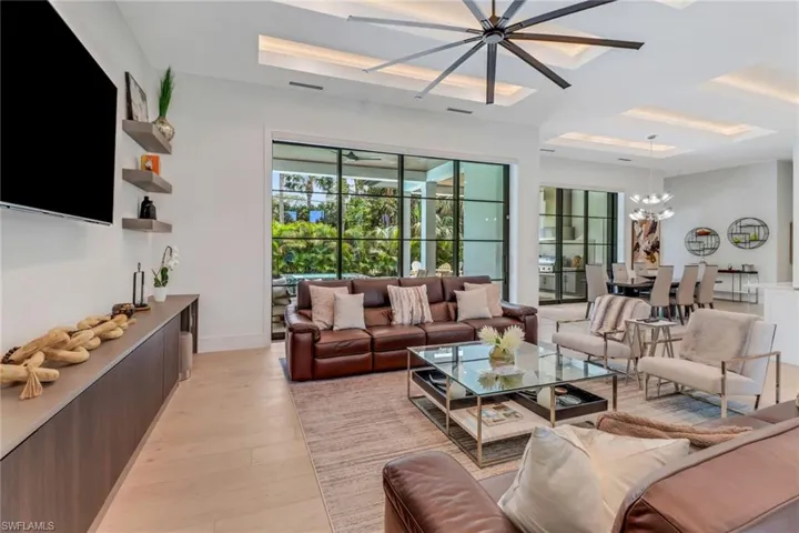 Living room featuring light wood-type flooring and ceiling fan with notable chandelier